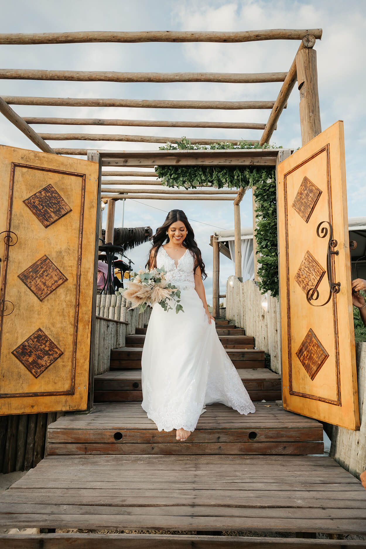 Noiva descendo as escadas na entrada do seu casamento na praia