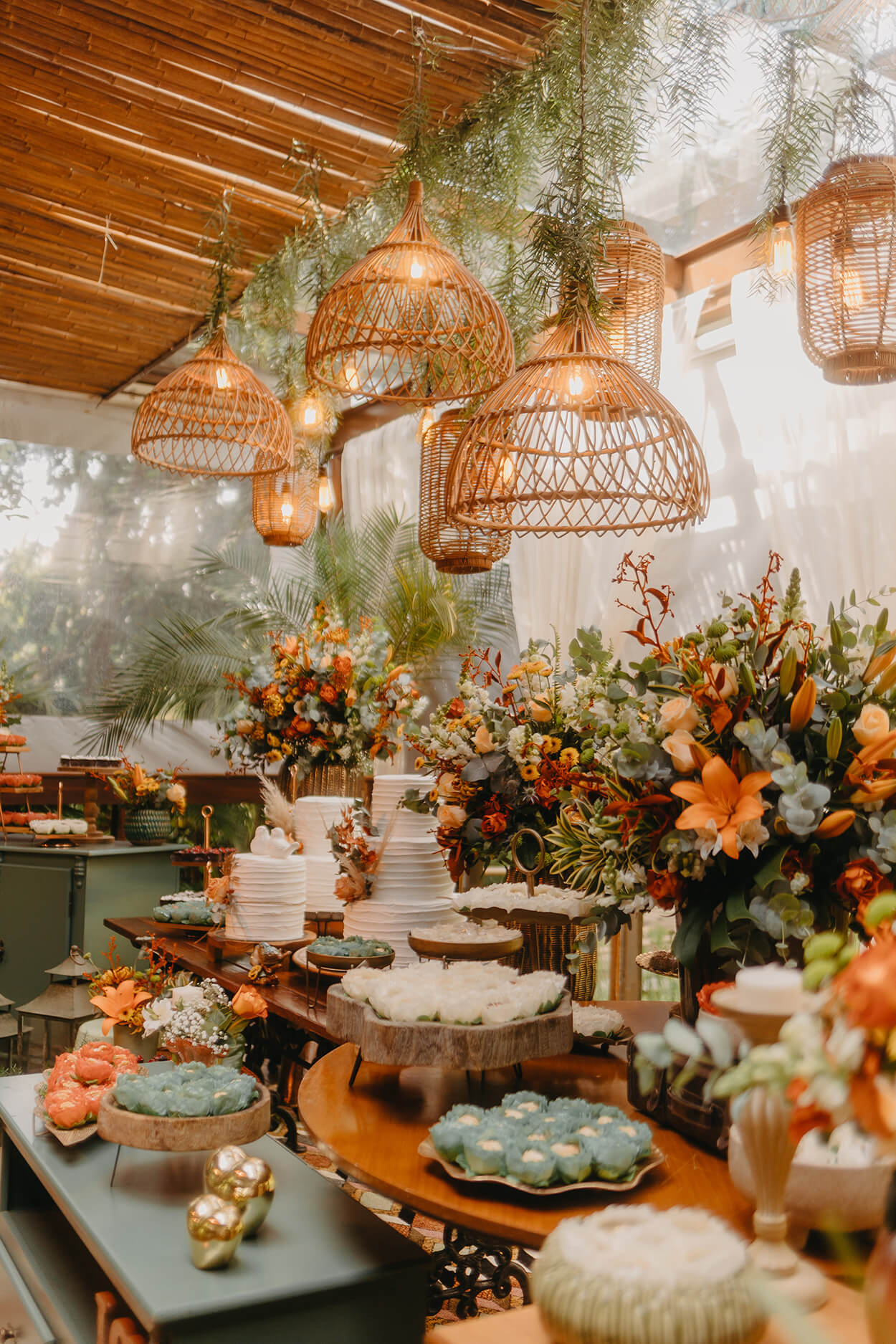 Mesa com doces de casamento flores laranjas e luminárias rústicas