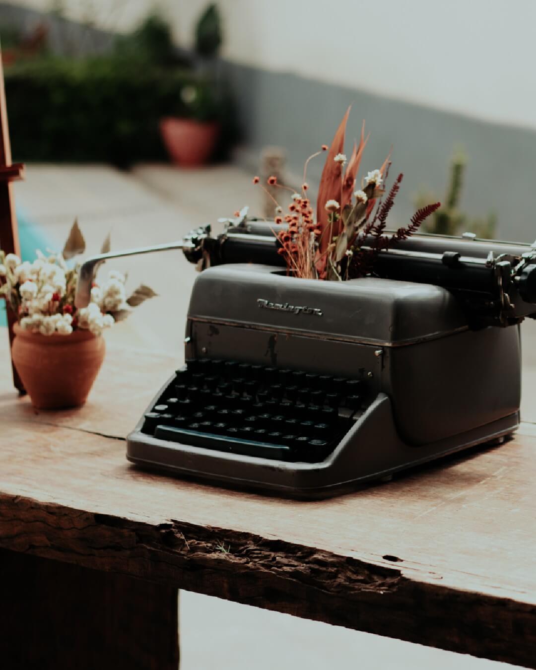 máquina de escrever cinza com flores em cima