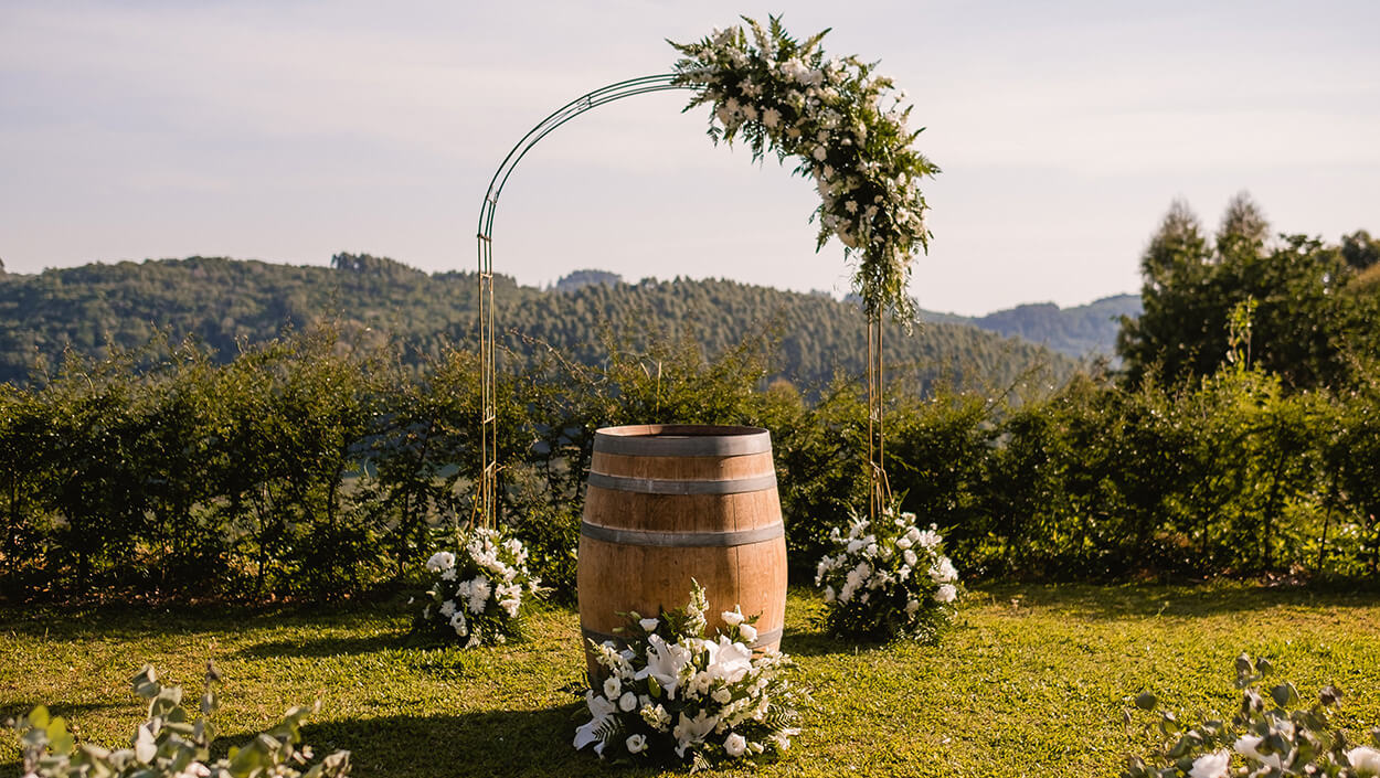 Altar de casamento com barril e arco metalizado com arranjos de flores brancas