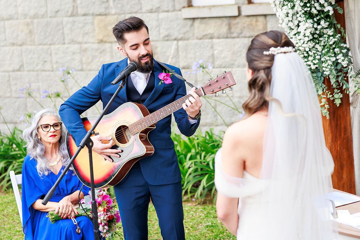 Noivo tocando violão e cantando no microfone para a noiva