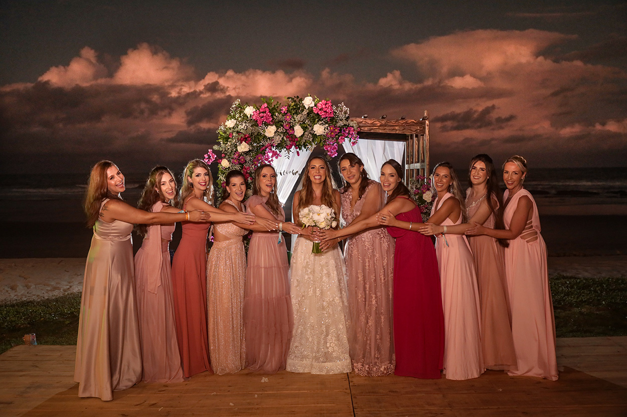 Madrinhas com vestidos cor de rosa ao lado da noiva segurando o buque