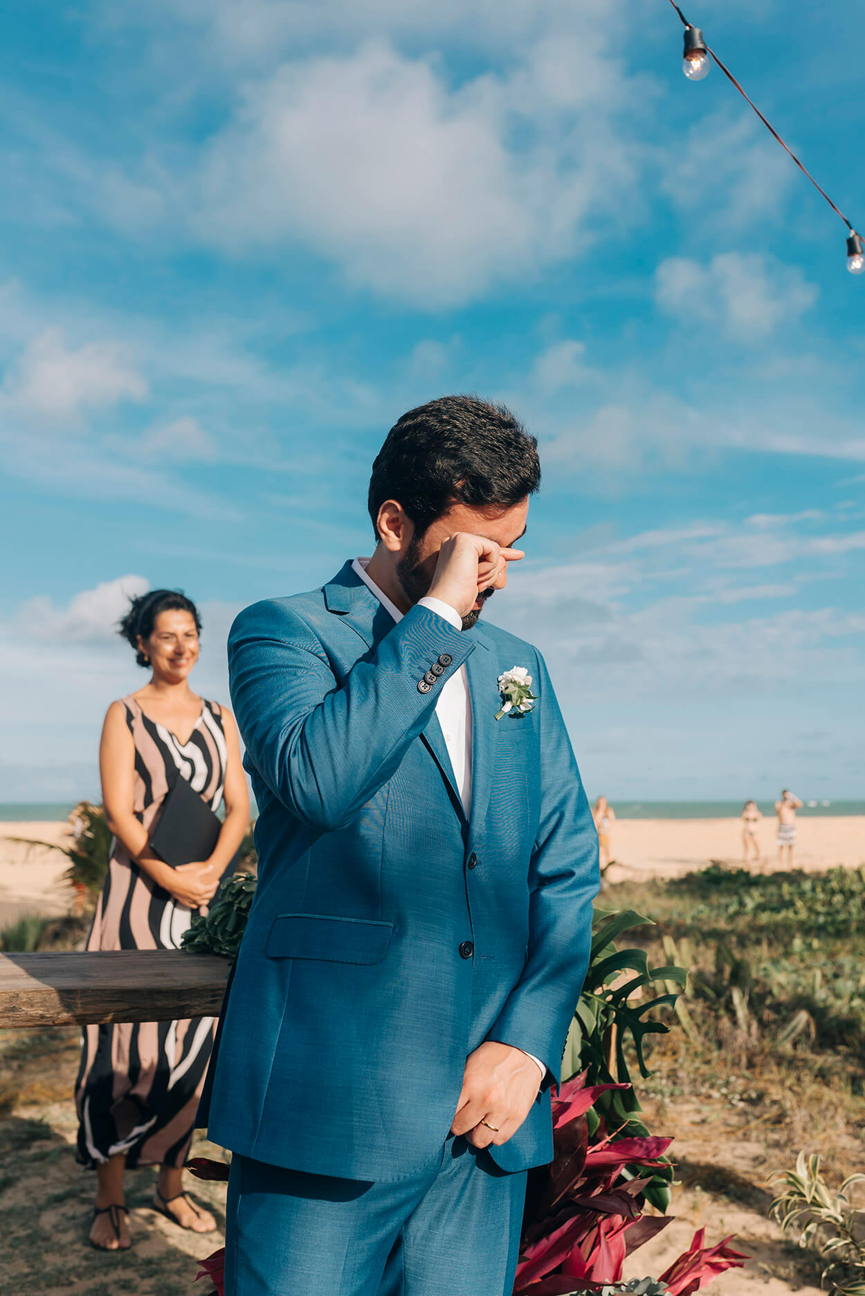 Noivo com terno azul emocionado no altar na praia