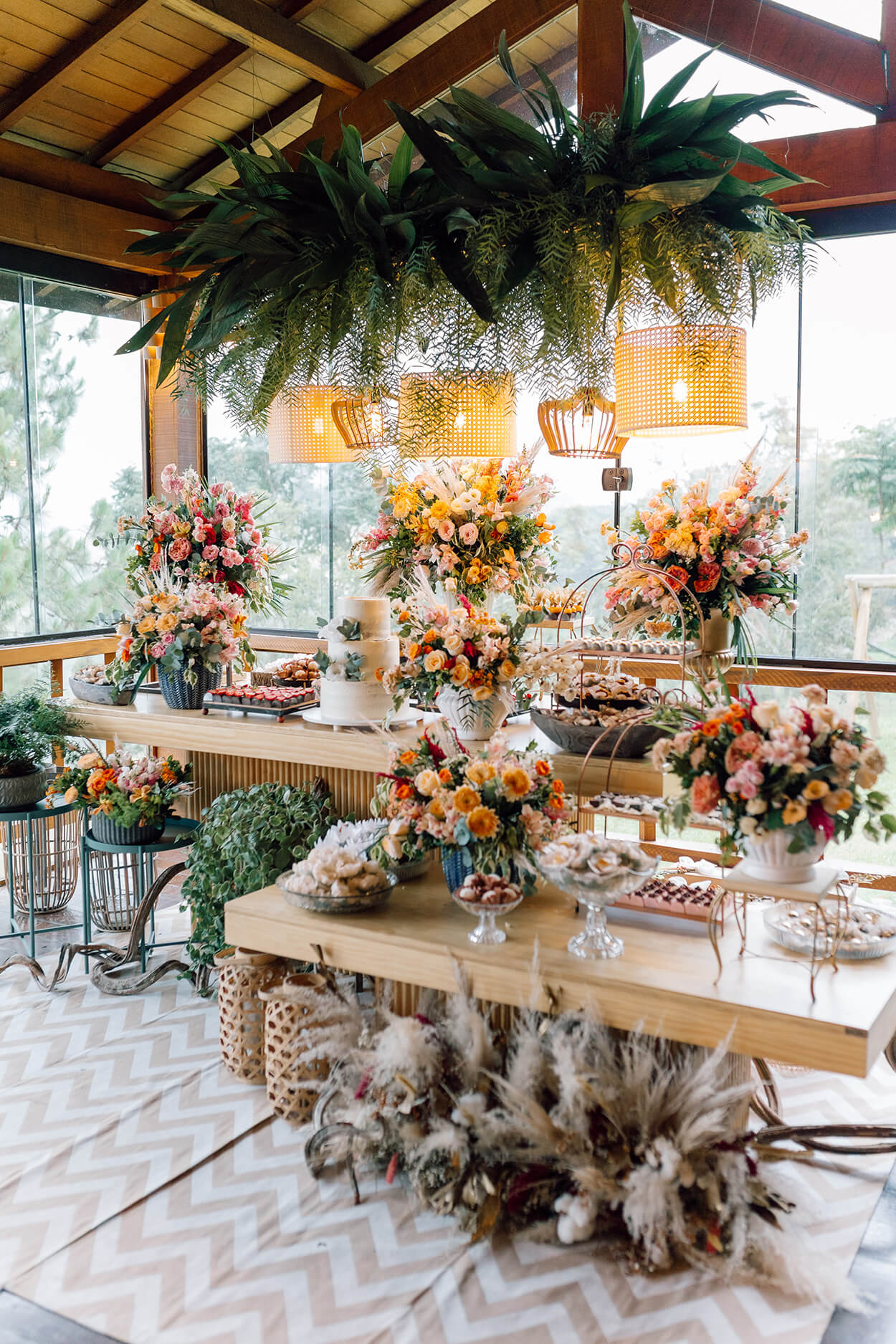 Mesa com bolo de casamenot e arranjos com flores coloridas
