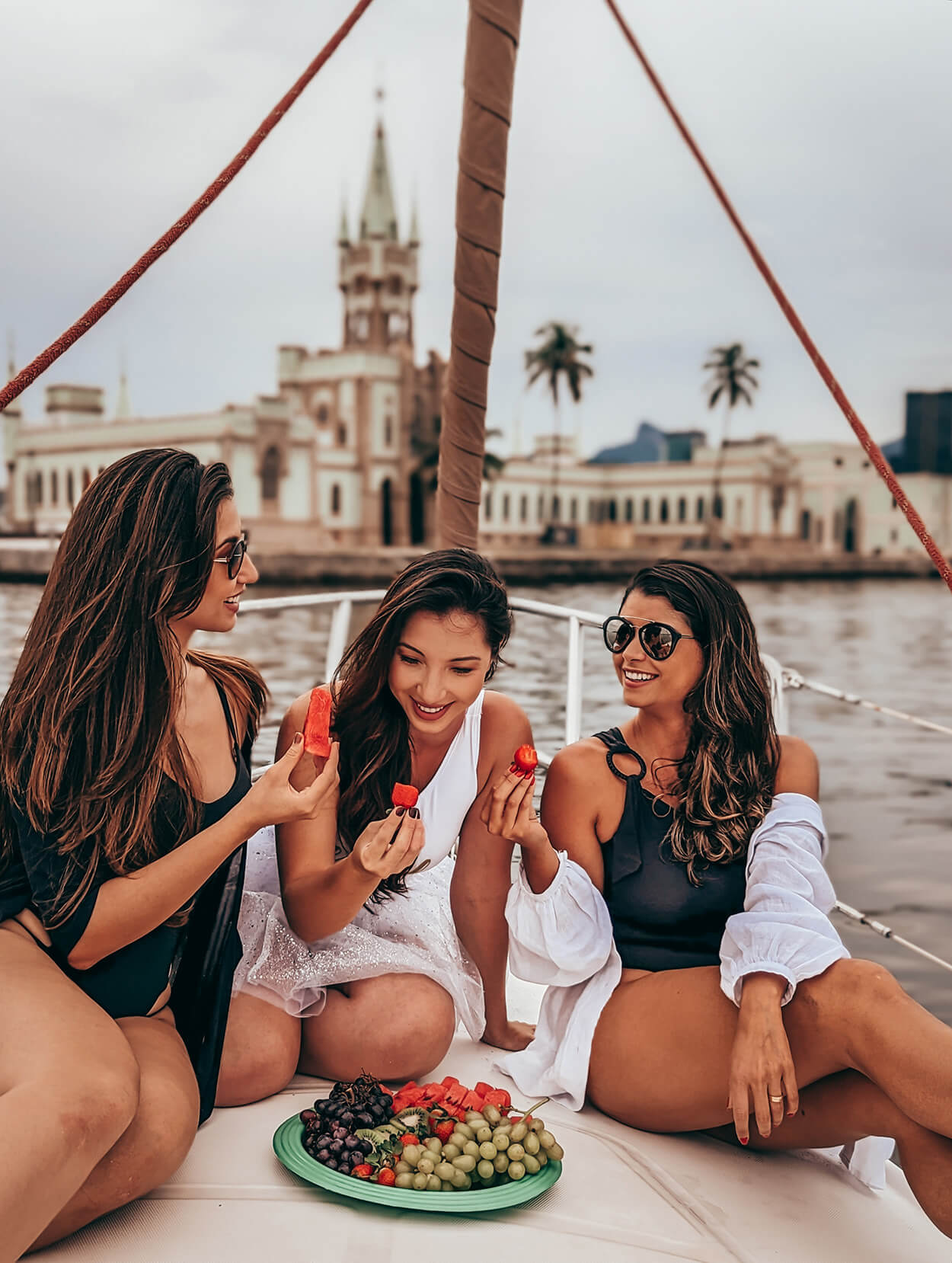 Três mulheres no veleiro comendo frutas e dando risada