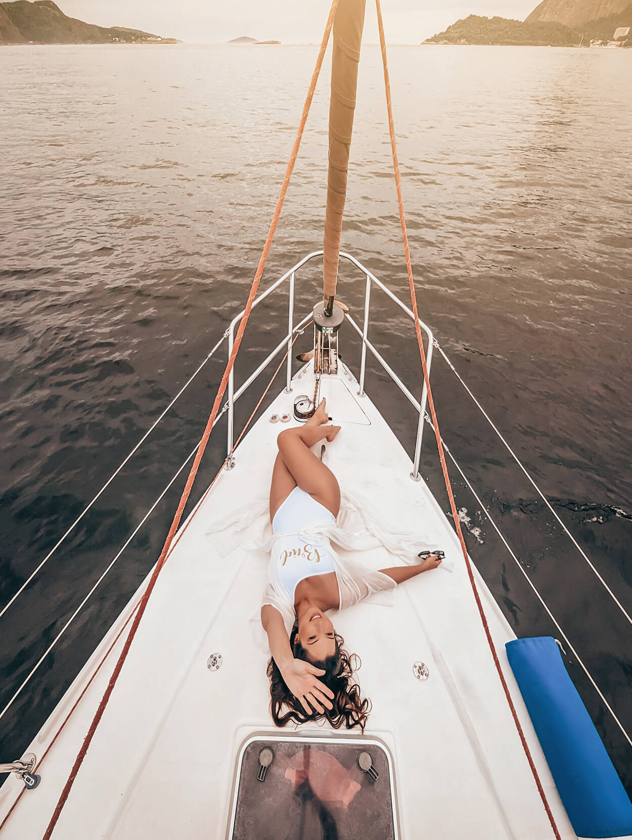 Mulher com maiô branco deitada no veleiro