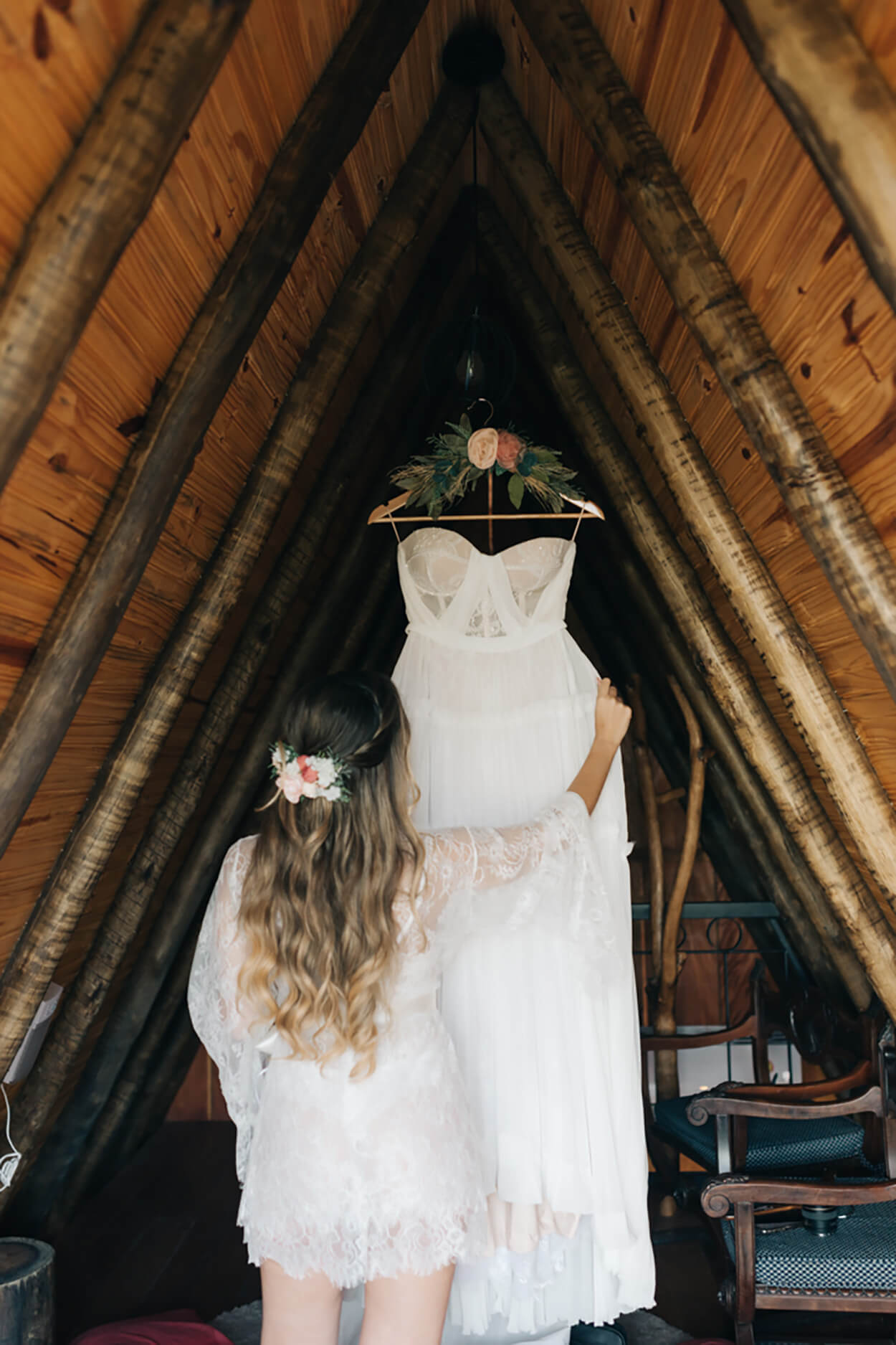 Mulher olhando vestido de noiva no cabide dentro da cabana