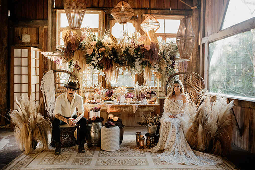 noivos sentados em cadeiras pavão em decoração de casamento boho