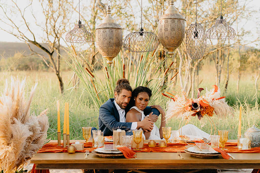 noivos se abraçando em mesa com decoração de casamento com folhas secas e tons de laranja