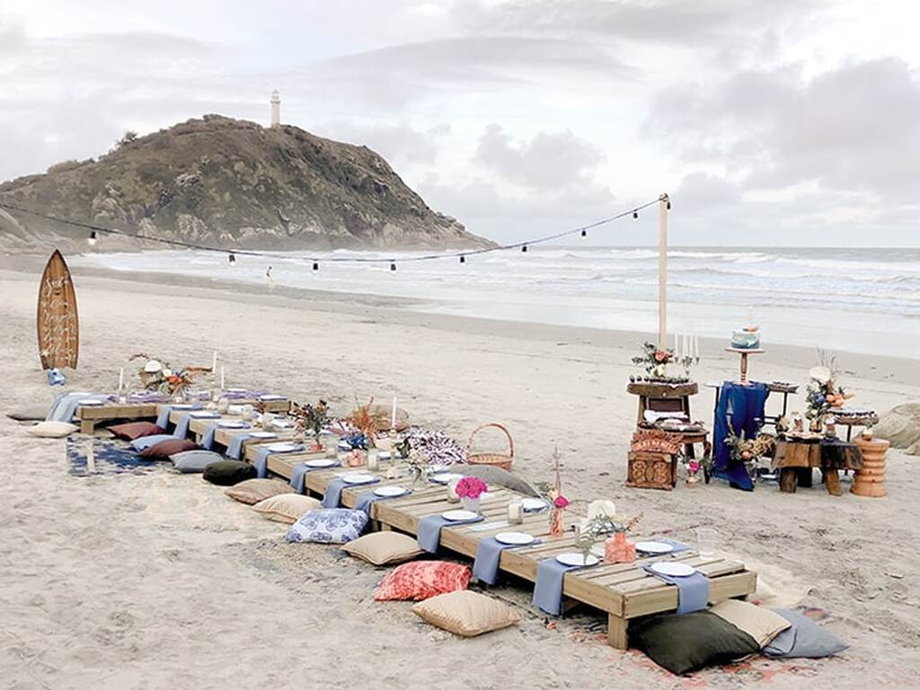 decoração de casamento na praia mesa comunitária e almofadas para sentar na areia