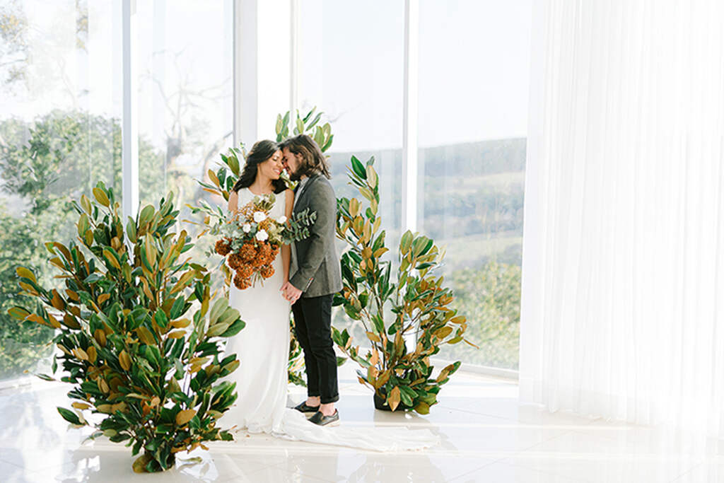 noivos abraçados entre folhagens como decoração de casamento sustentável 