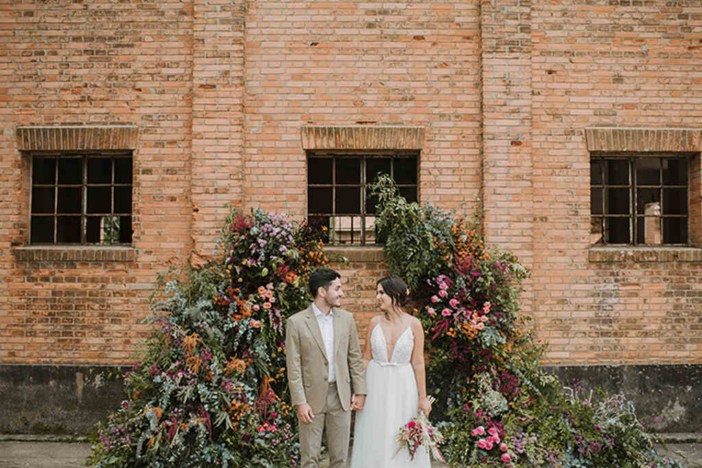 noivos em casamento ao ar livre com decoração em arco de flores