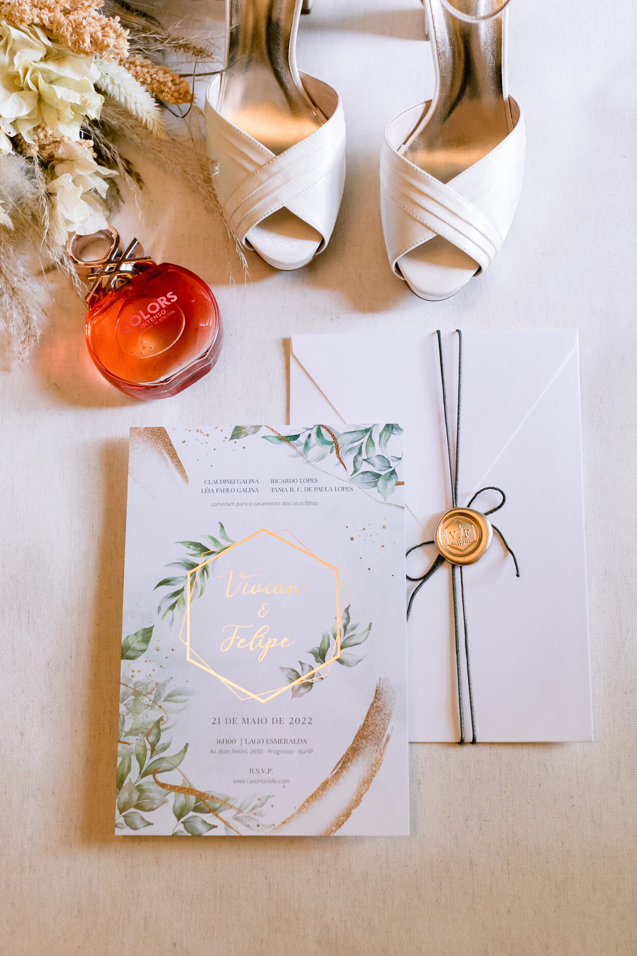 Sandália brnaca peep toe com perfume vermelho e ocnvite de casamento branco com tem floral e detalhes em dourado
