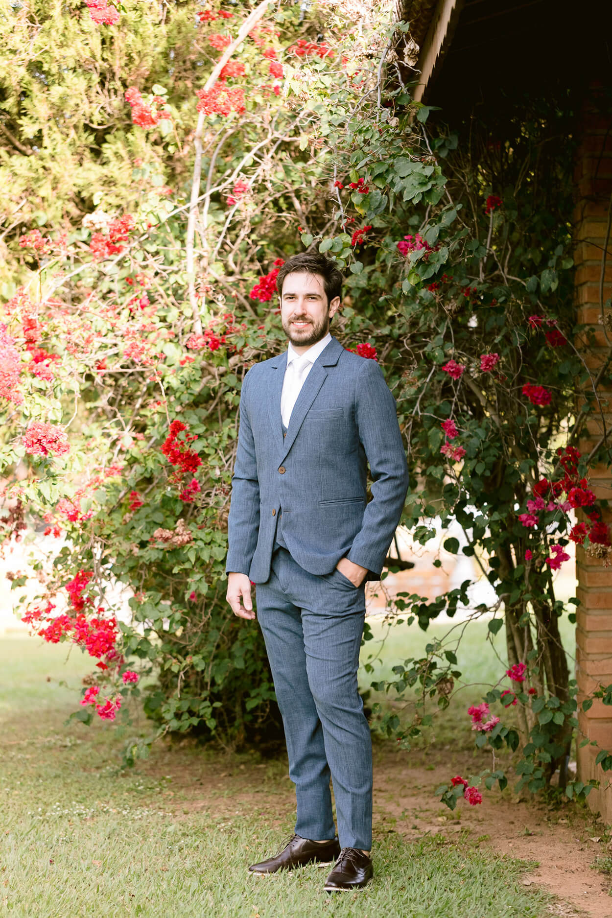 Noivo com terno azul e gravata branca no jardim