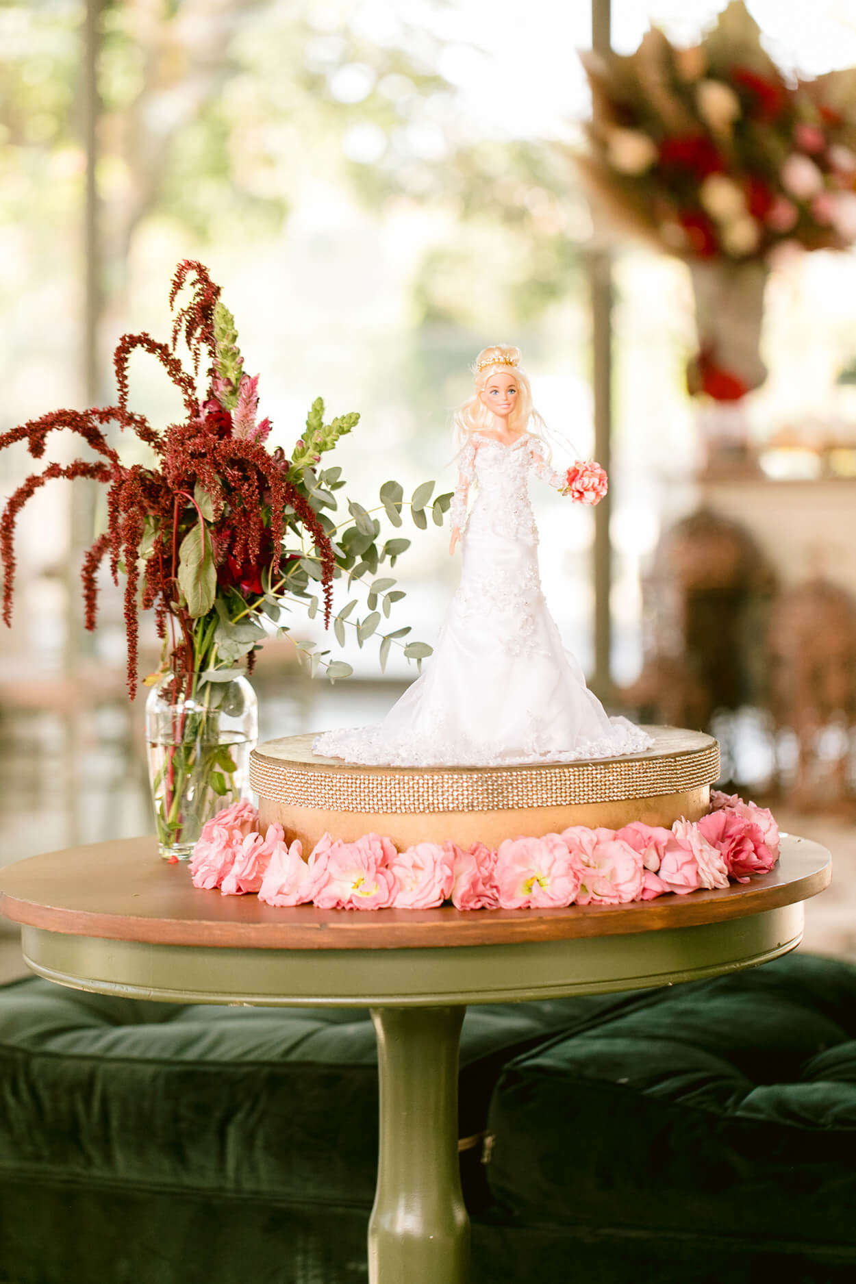 Mesa verde sage com barbie vetsida de noiva carregando buquê cor de rosa