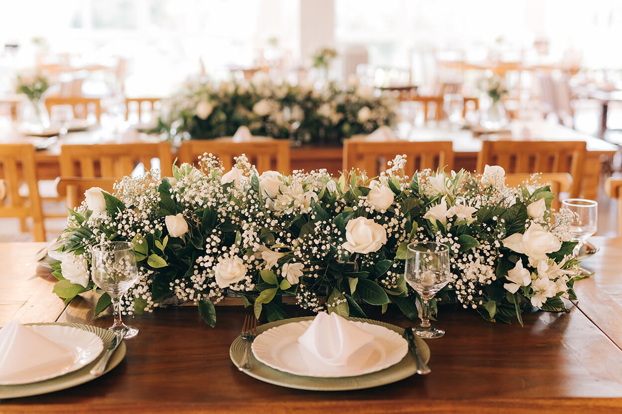 Mesa de madeira posta elegante com flores brancas e flor mosquitinho no centro de mesa