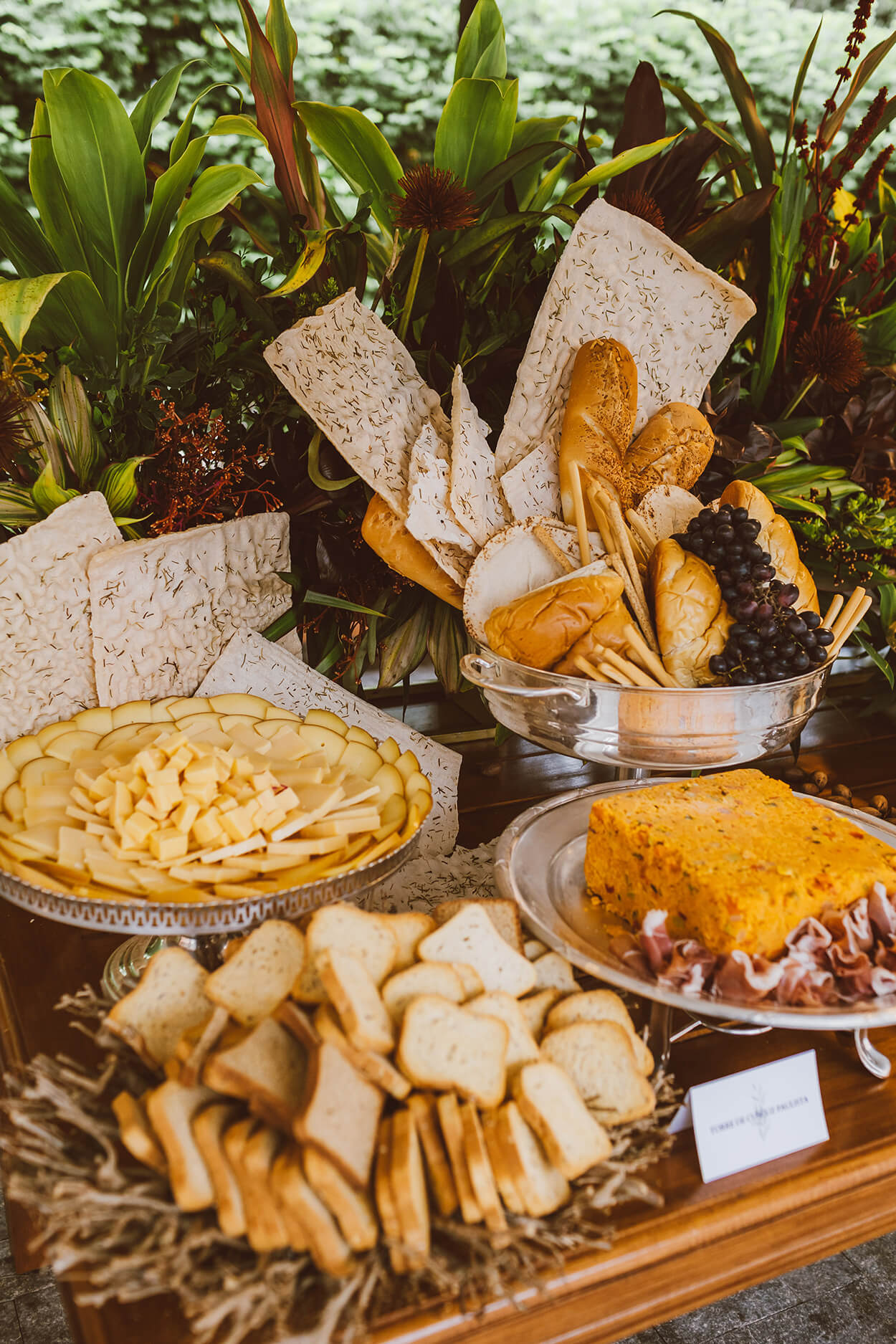Mesa com bandejas com queijos pães e torradas