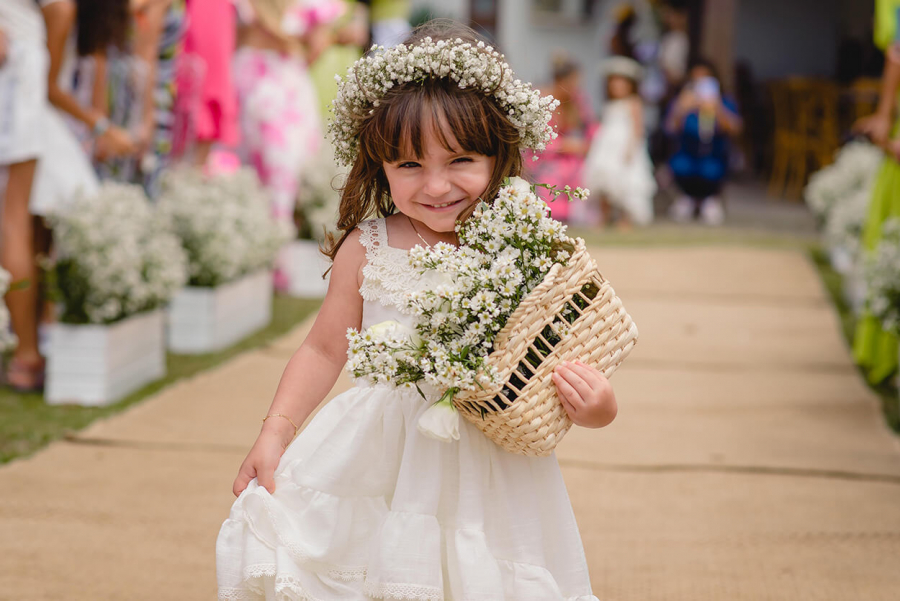 Florista com vestido branco e coroa de flores segurando cesta com flores brancas