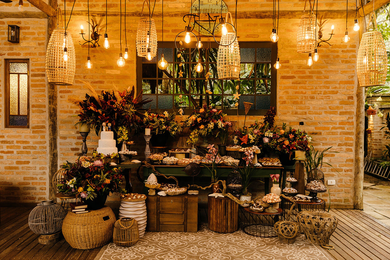 Mesa rustica com bolo de casamento com tres andares e arranjos com flores