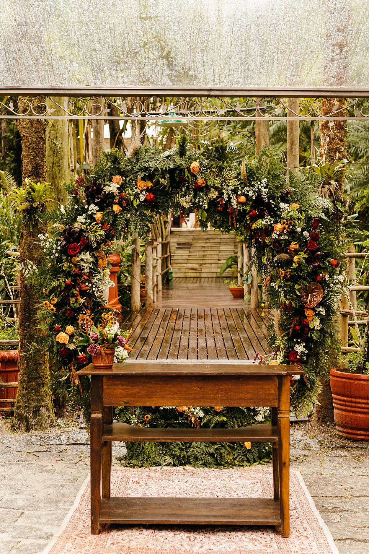 Altar com mesa de madeira e arco com flores e ramos