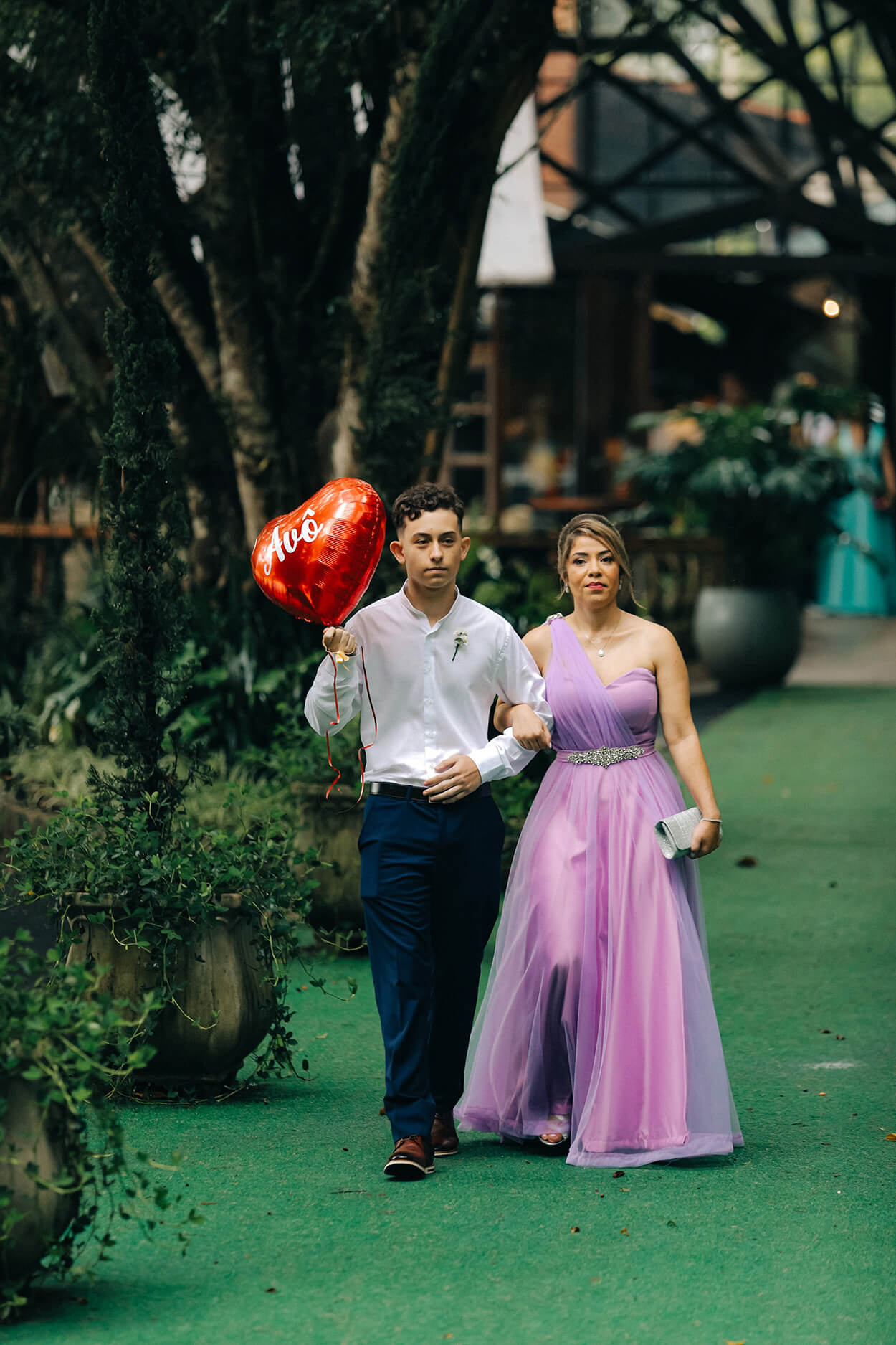 Padrinho segurnaod balão vermelhi e mulher com vestido lilás