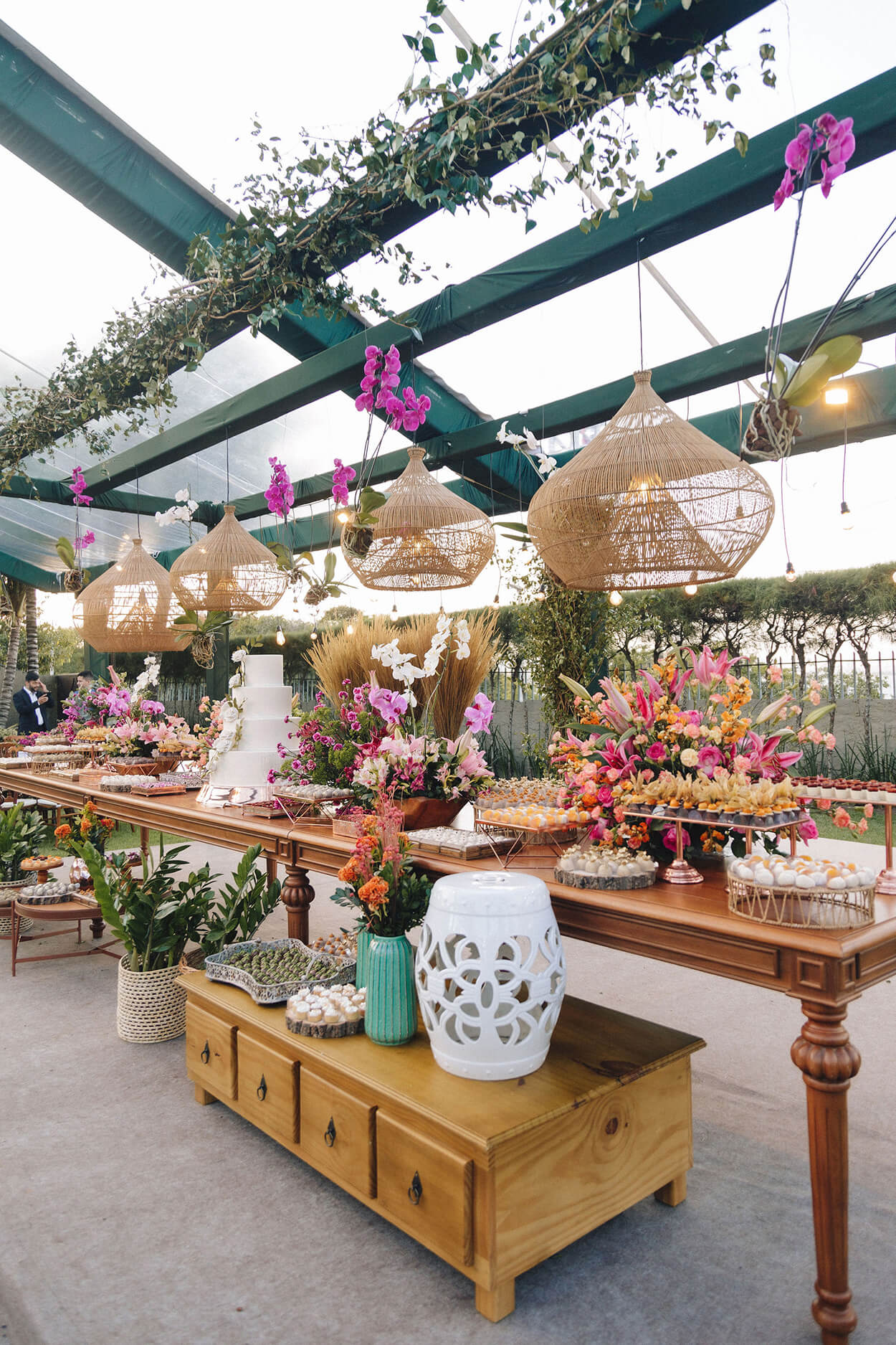 Mesa de madeira com bolo de casamento luminarias rusticas e arranjos com flores