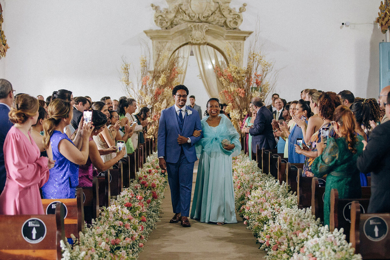 Entrada do noivo na igreja ao lado de sua mãe usando um vestido longo azul serenity