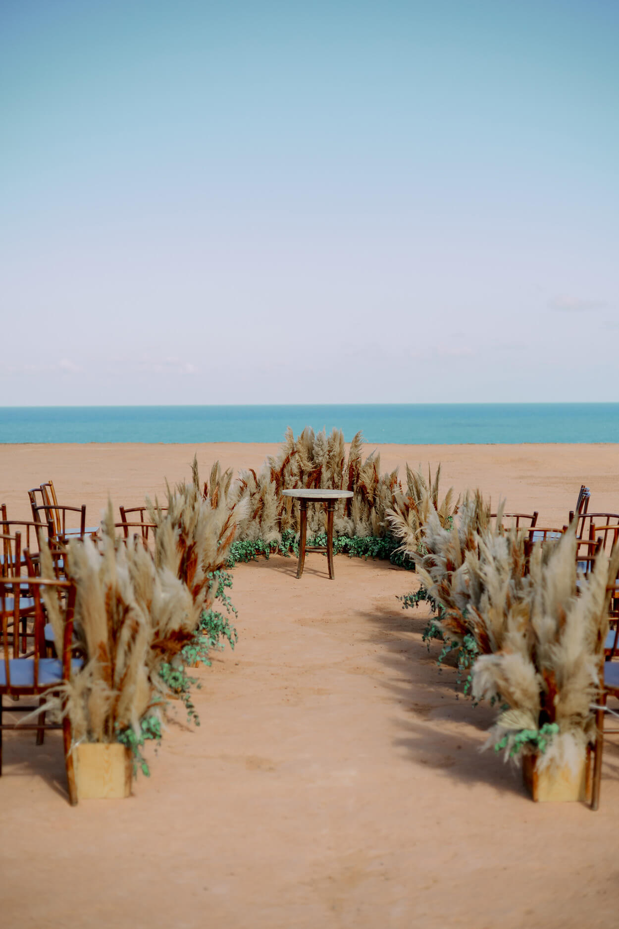 Cadeiras e altar decorados com capim dos pampas para casamenrto na praia