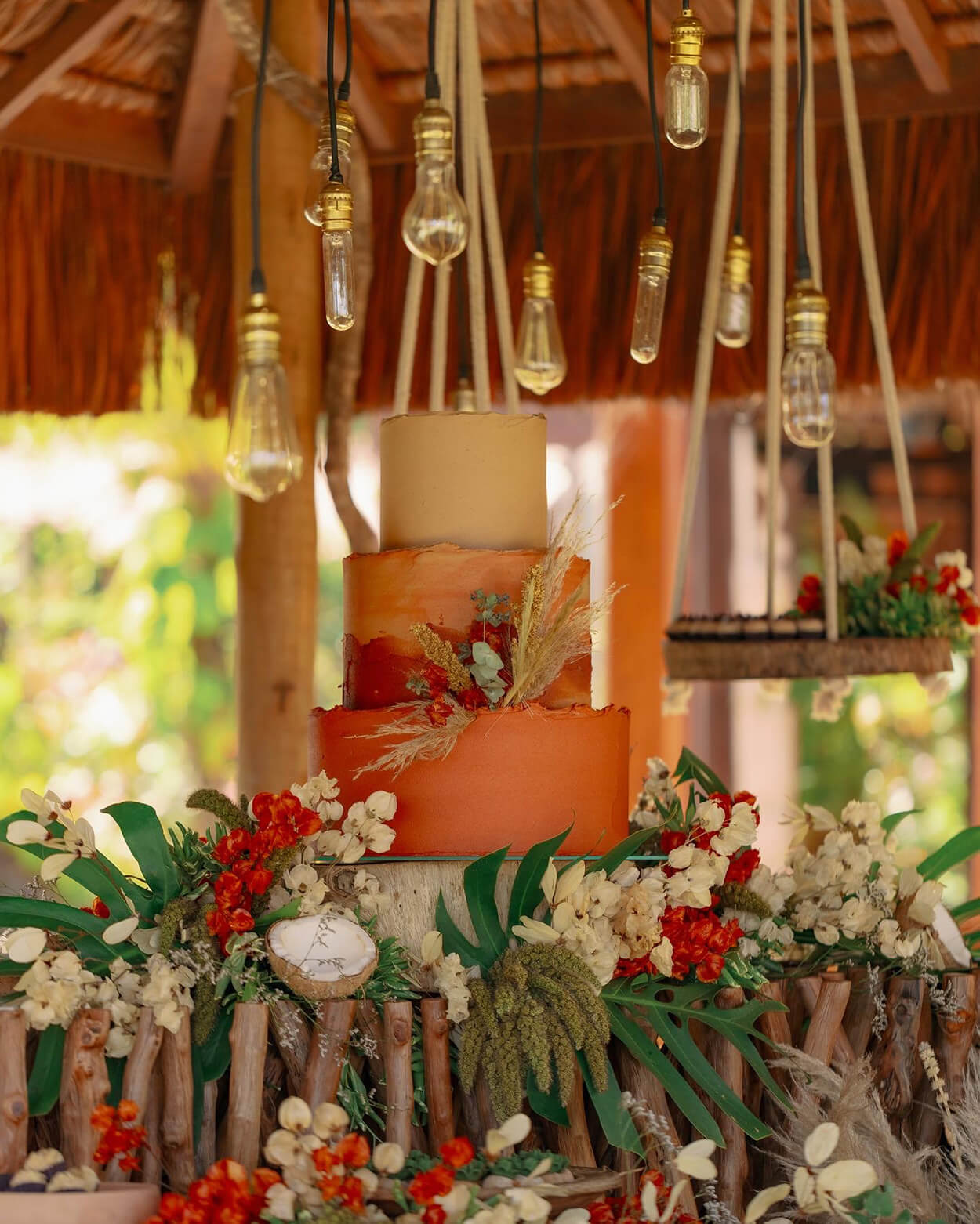 Mesa de madeira com Bolo de cassamento rustico com tres andares laranja e bege com capim dos pampas e flores
