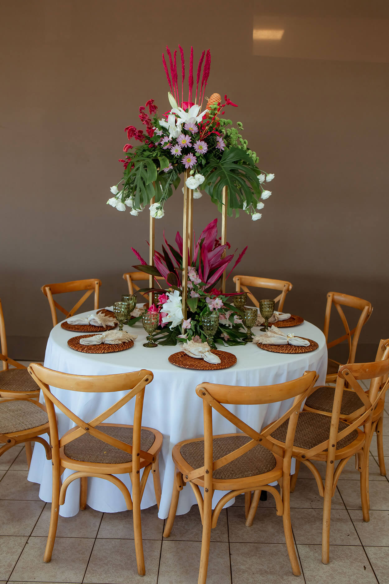 Mesa redonda com toalha branca com arranjos com flores brancas e rosas no centro