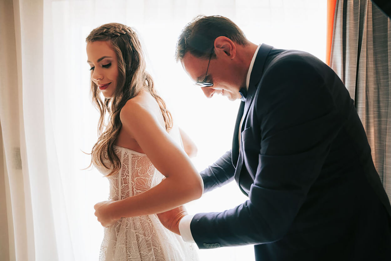 Pai da noiva ajudando a fechar o vestido