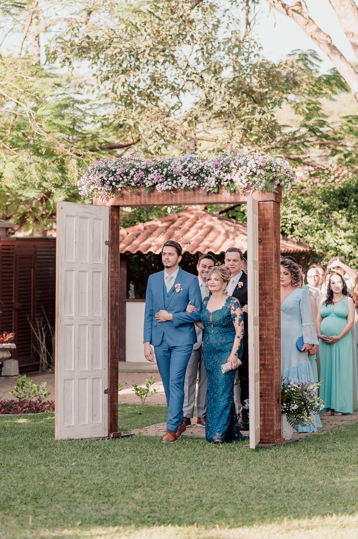 Entrada do noivo ao lado da mae com vestido azul
