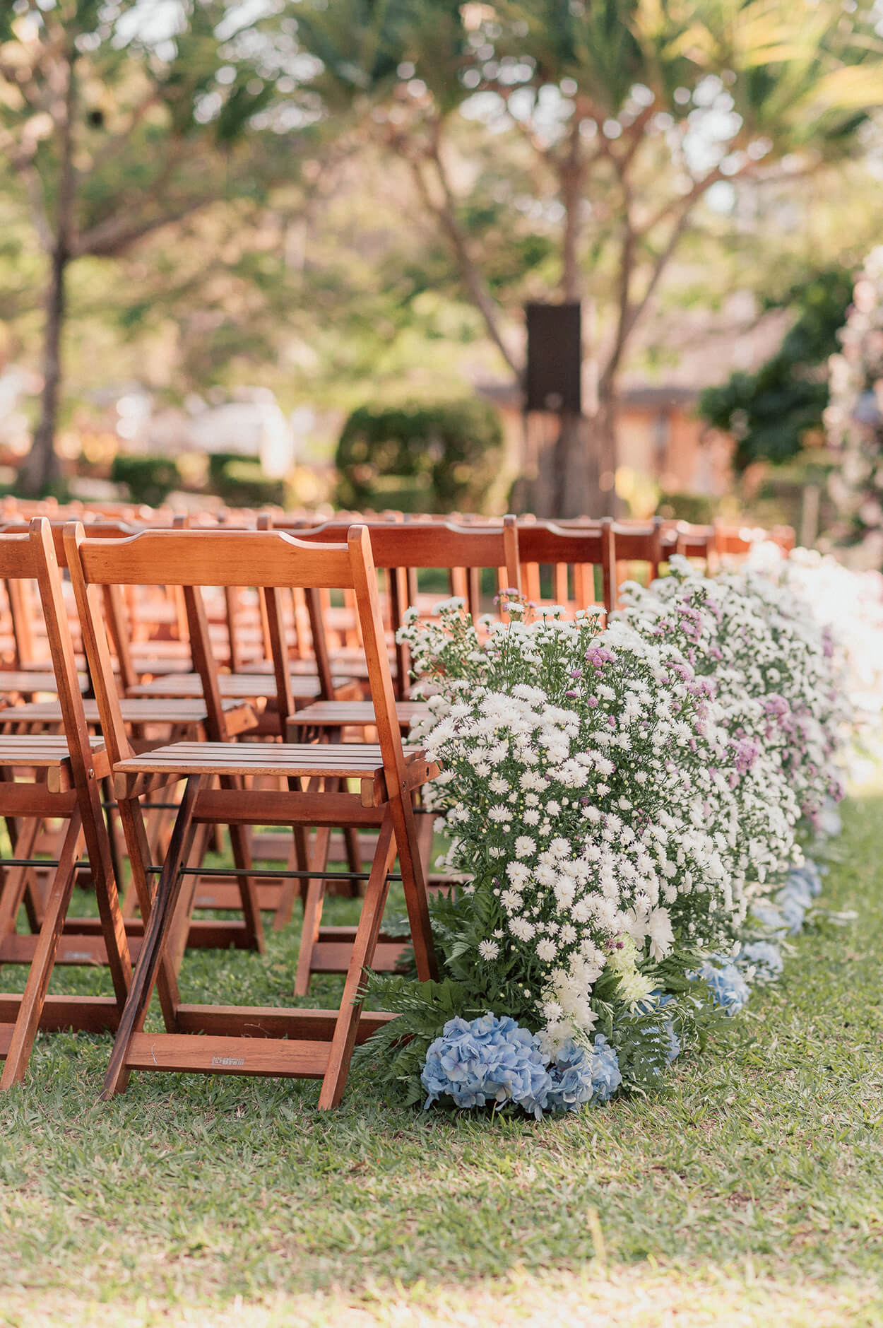 cadeiras de madeira com arranjos de flores brancas azuis e lilas