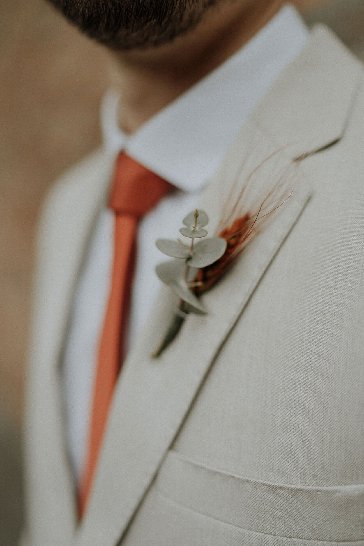 Vista de lado do noivo com terno algodão cru com gravata laranja