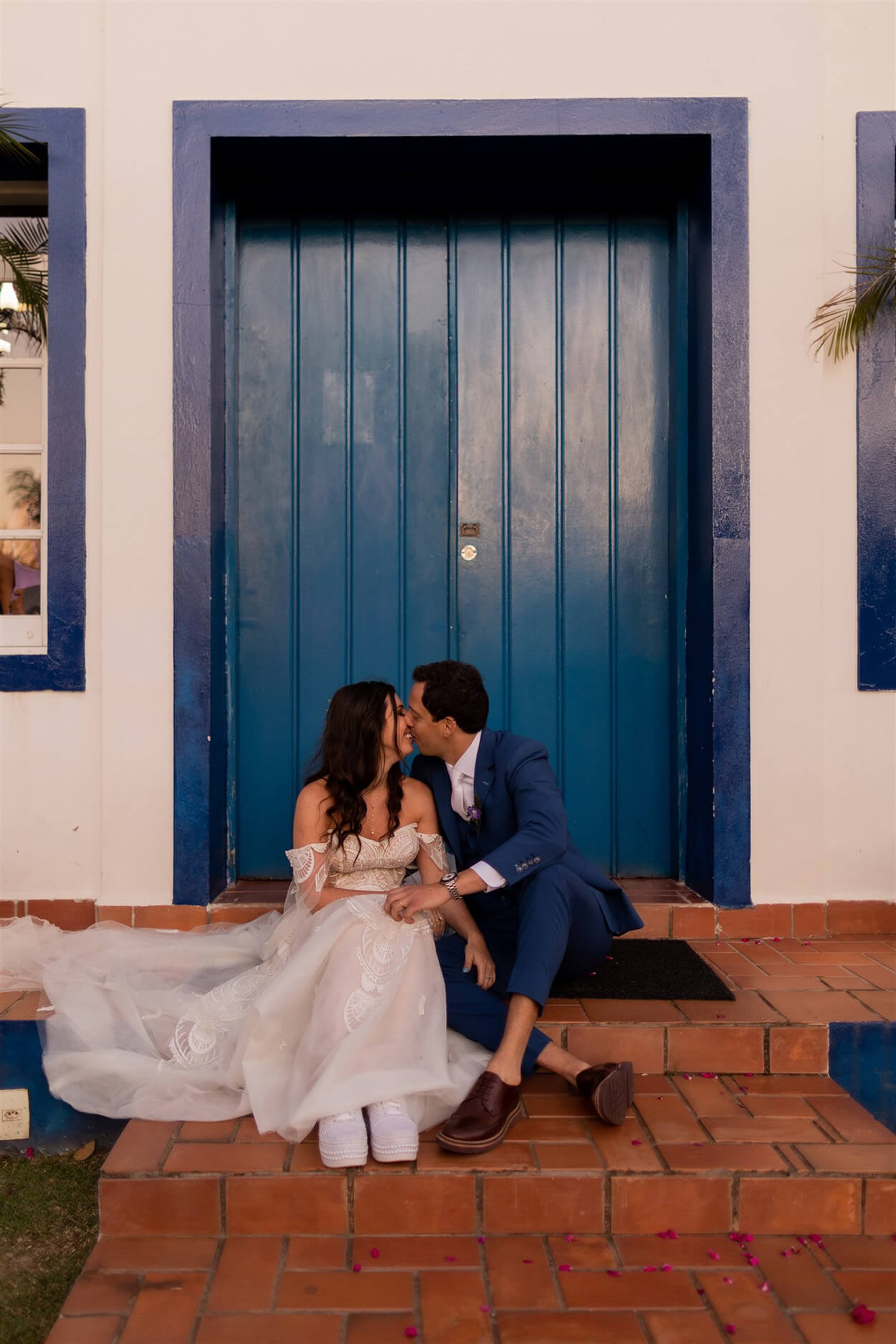 Noivos se beijando em frente a porta azul