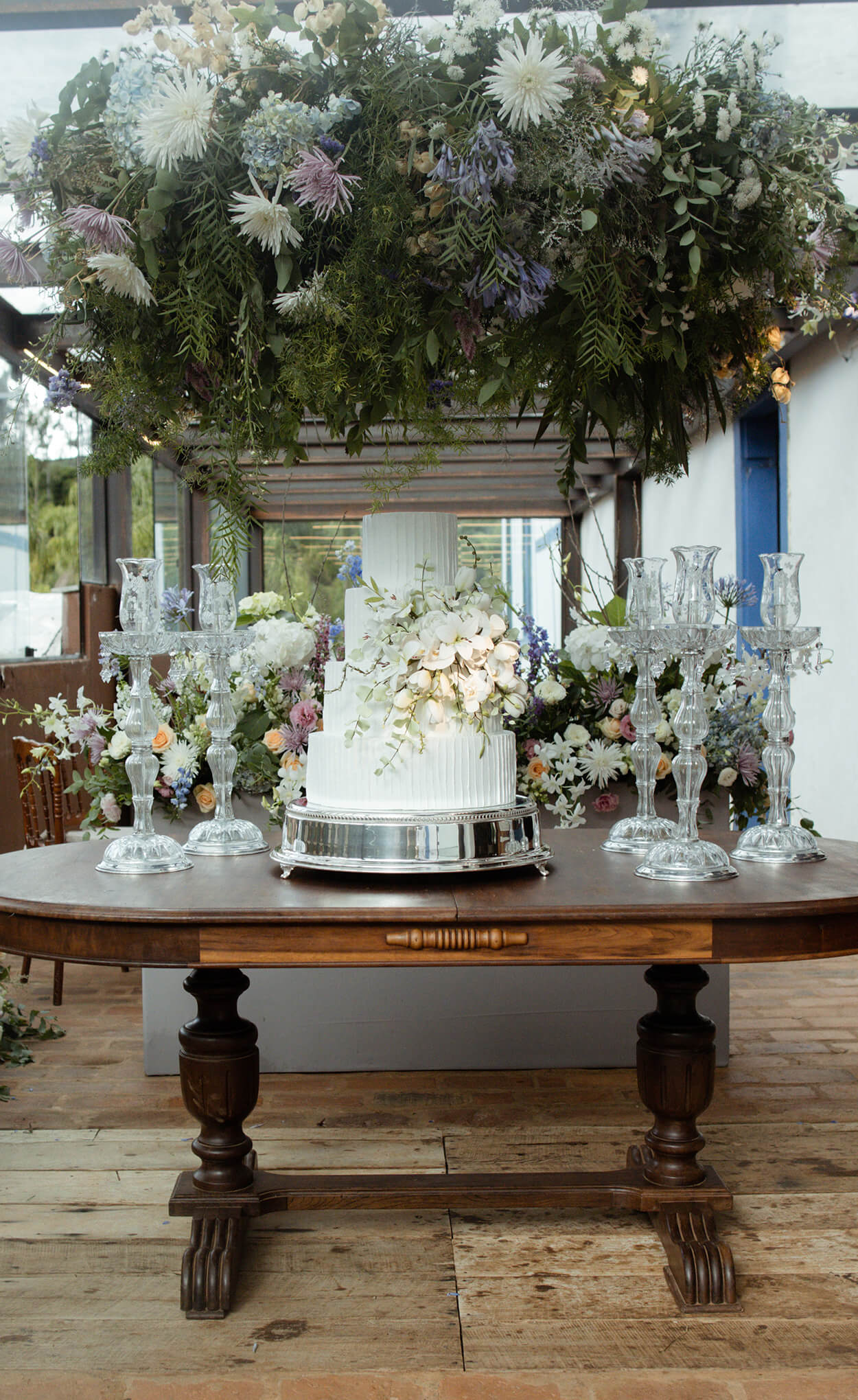Mesa antiga com bolo de casamento com quatro andares com flores brancas