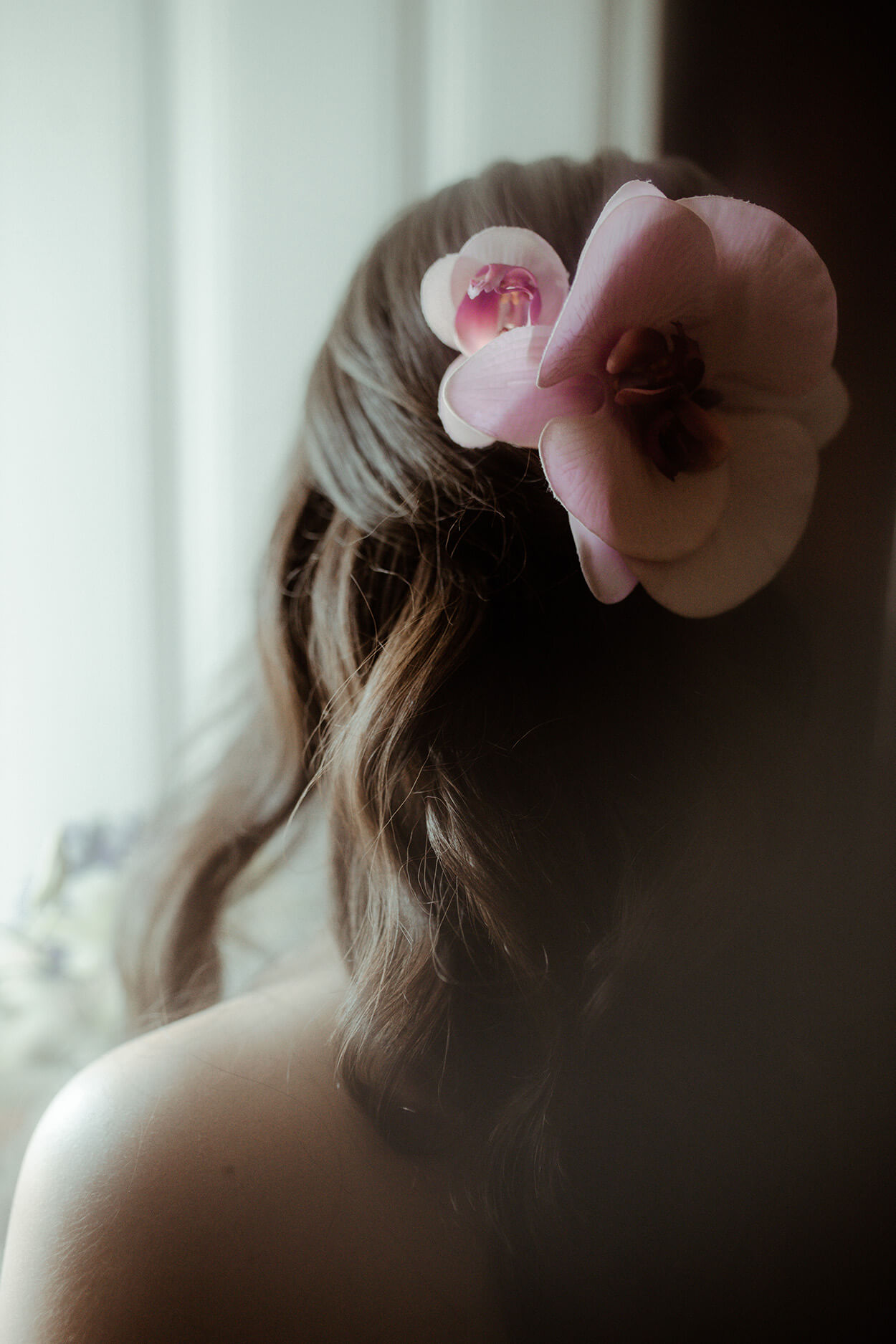 Noiva de costas com penteados semi preso com flor cor de rosa