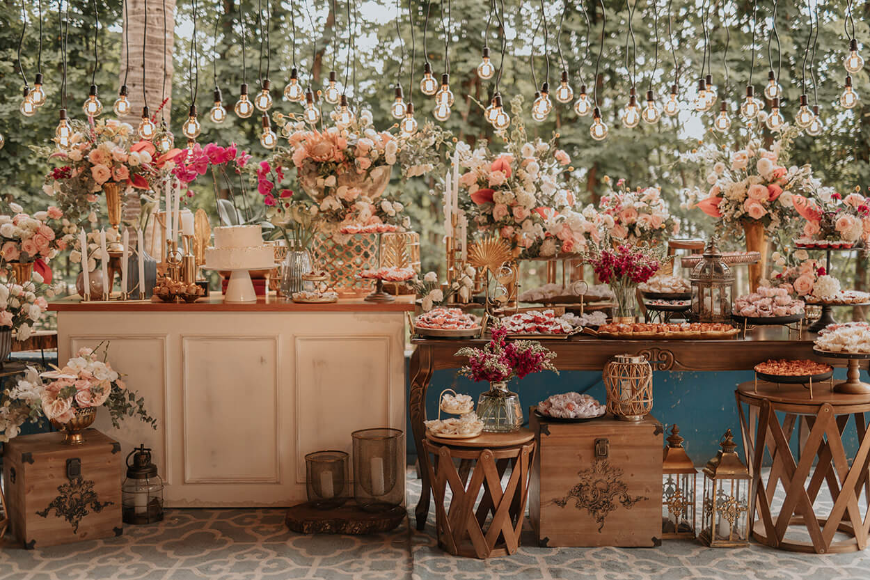 mesas com bolo de casamento com vasos de flores brancas e rosas