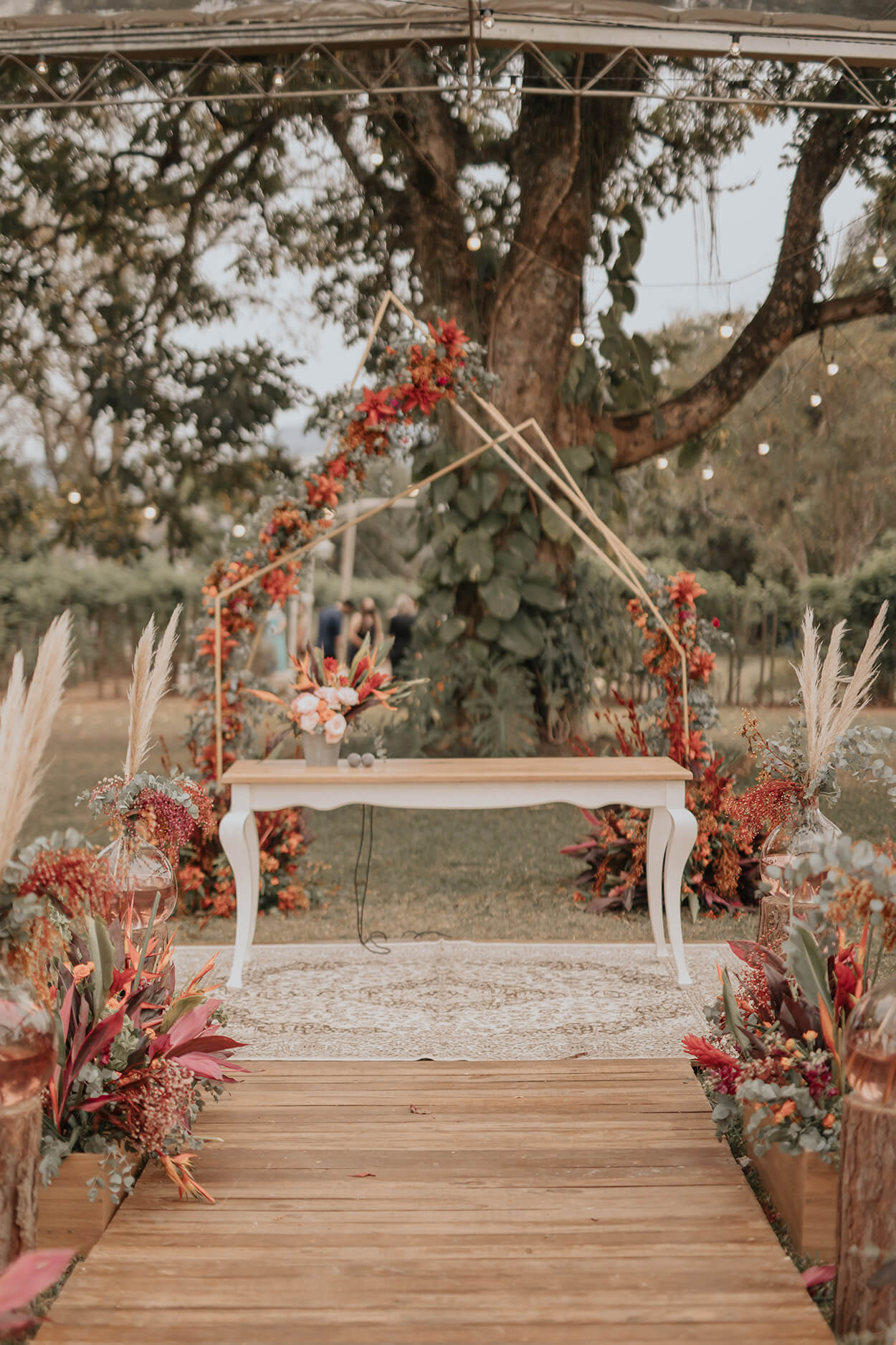 altar com mesa rústica branca com arco geométrico com flores laranjas