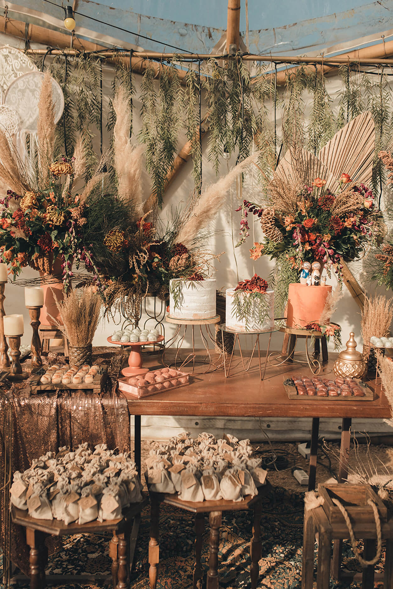 Mesa com trio de bolos de casamento com vasos com flores