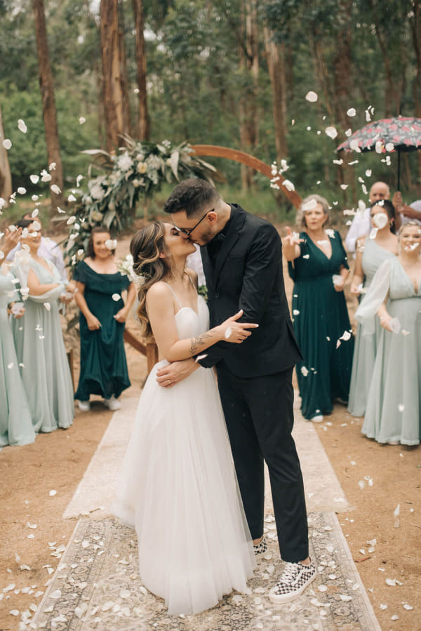 capa post: Noivos se beijando enquanto os convidados com petalas