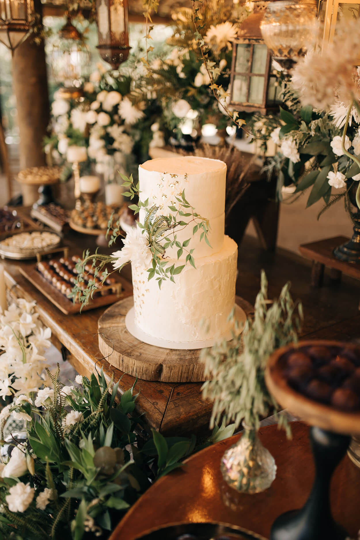 mesa de madeira com bolo de casamento branco com dois andares e flores