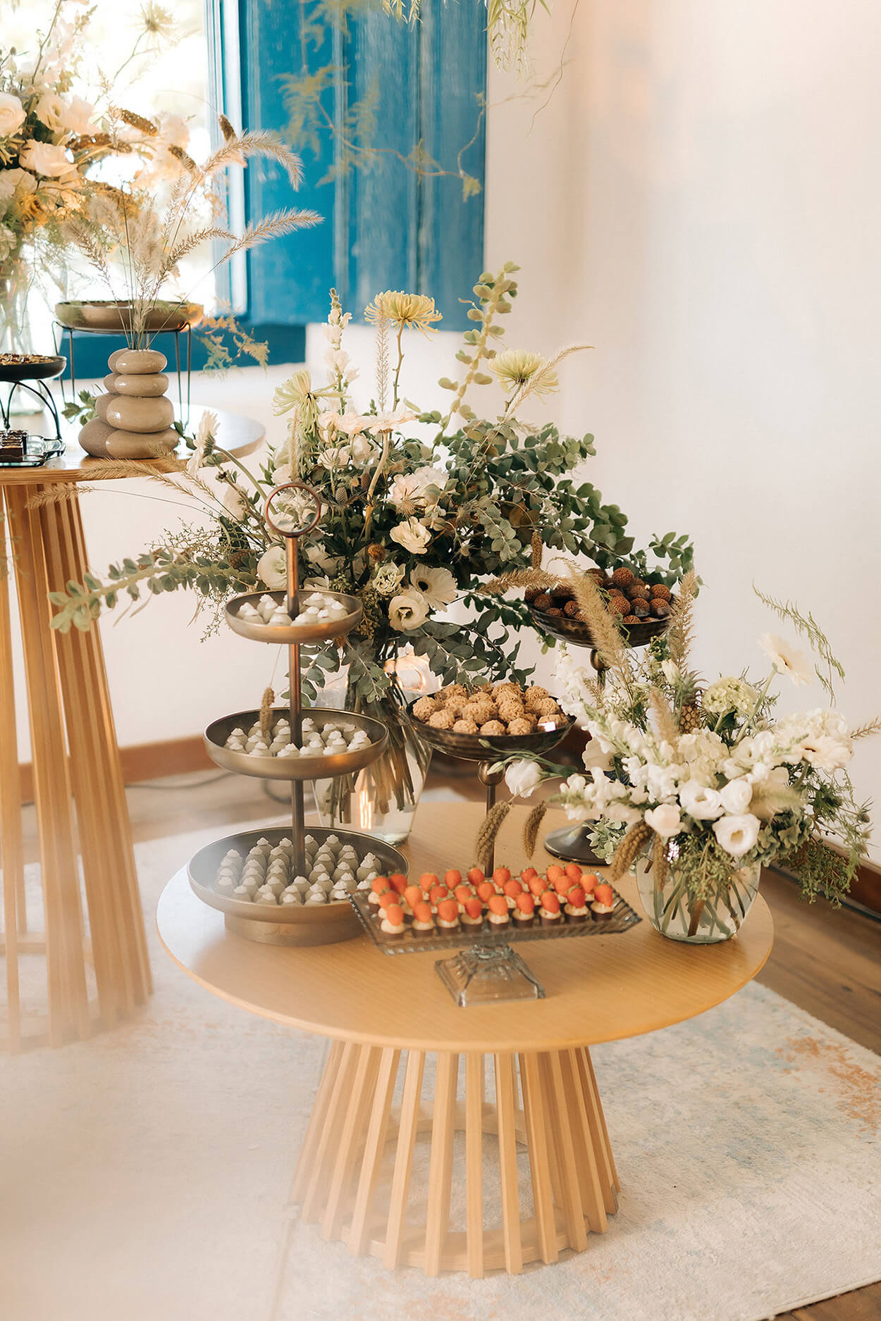 salão com mesas redondads com flores e bandejas de doces