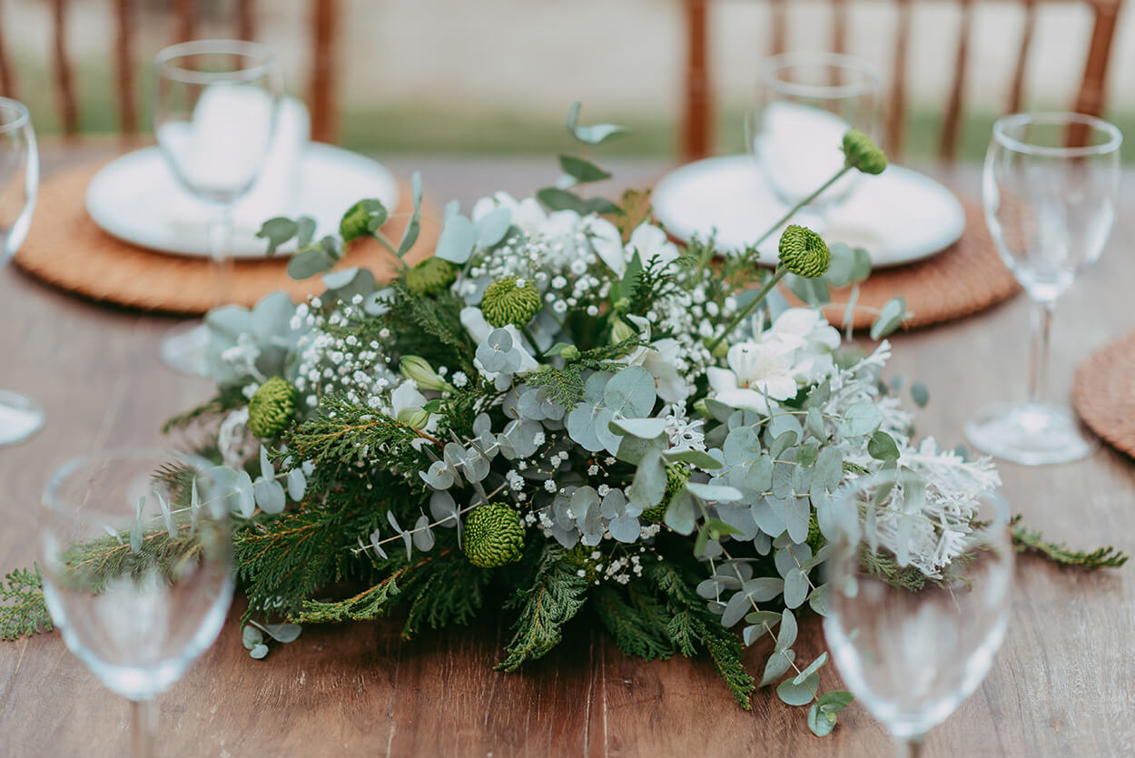 centro de mesa com arranjo com flores brancas ramos de eucalipto e de pinheiro