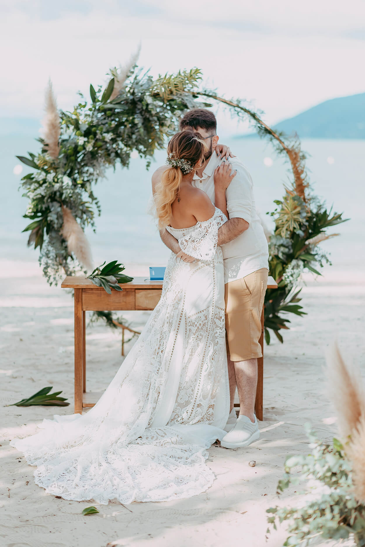 Noivos se beijando na cerimonia de casamento na praia