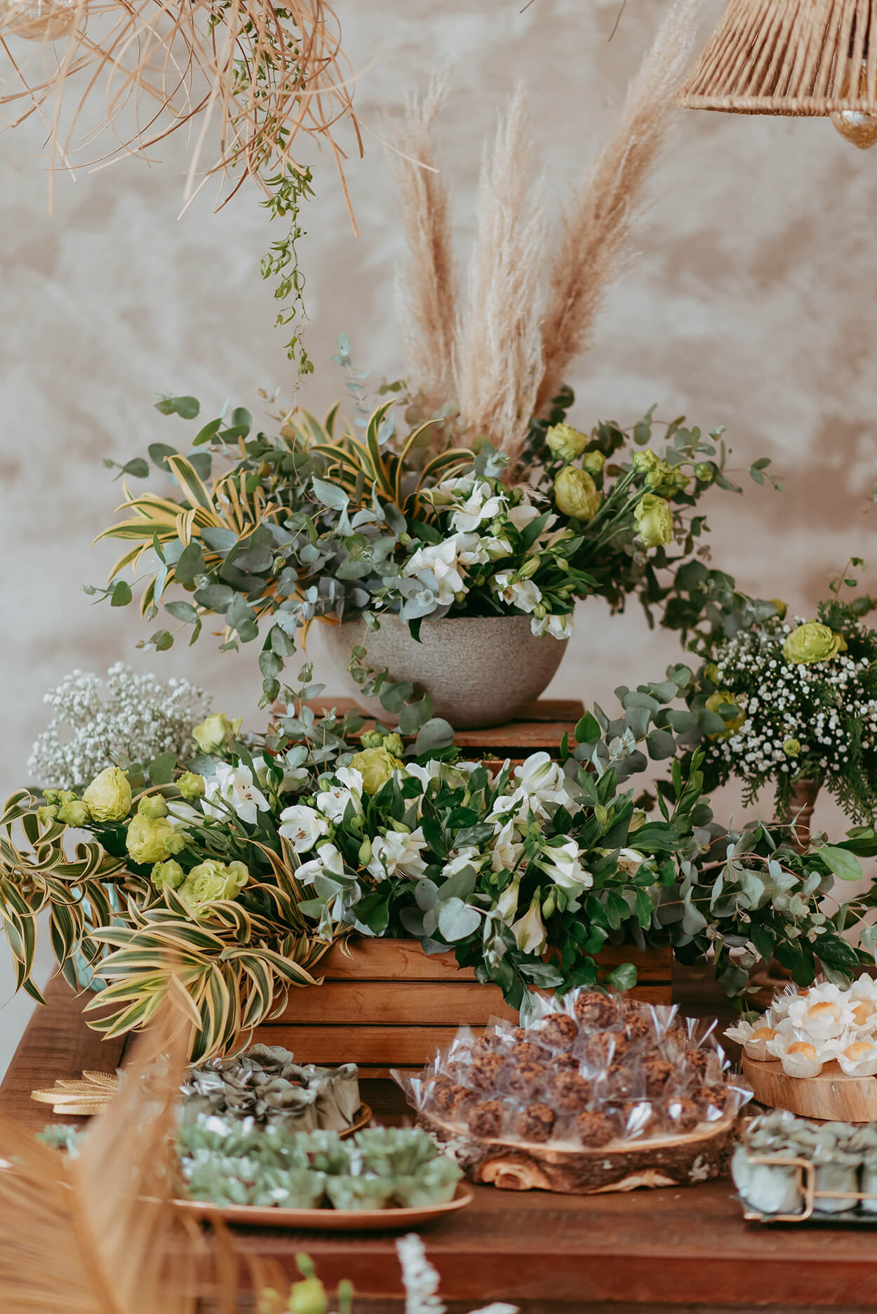 mesa com vasos de flores capim dos pampas folhagens e doces de casamento