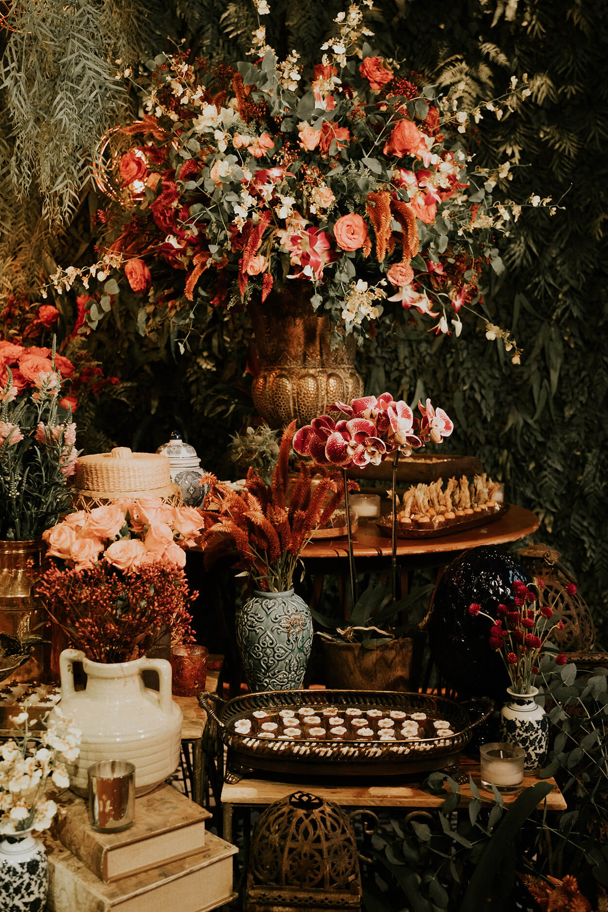 Mesa redondad de madeira com vasos de flroes e bandejas com doces