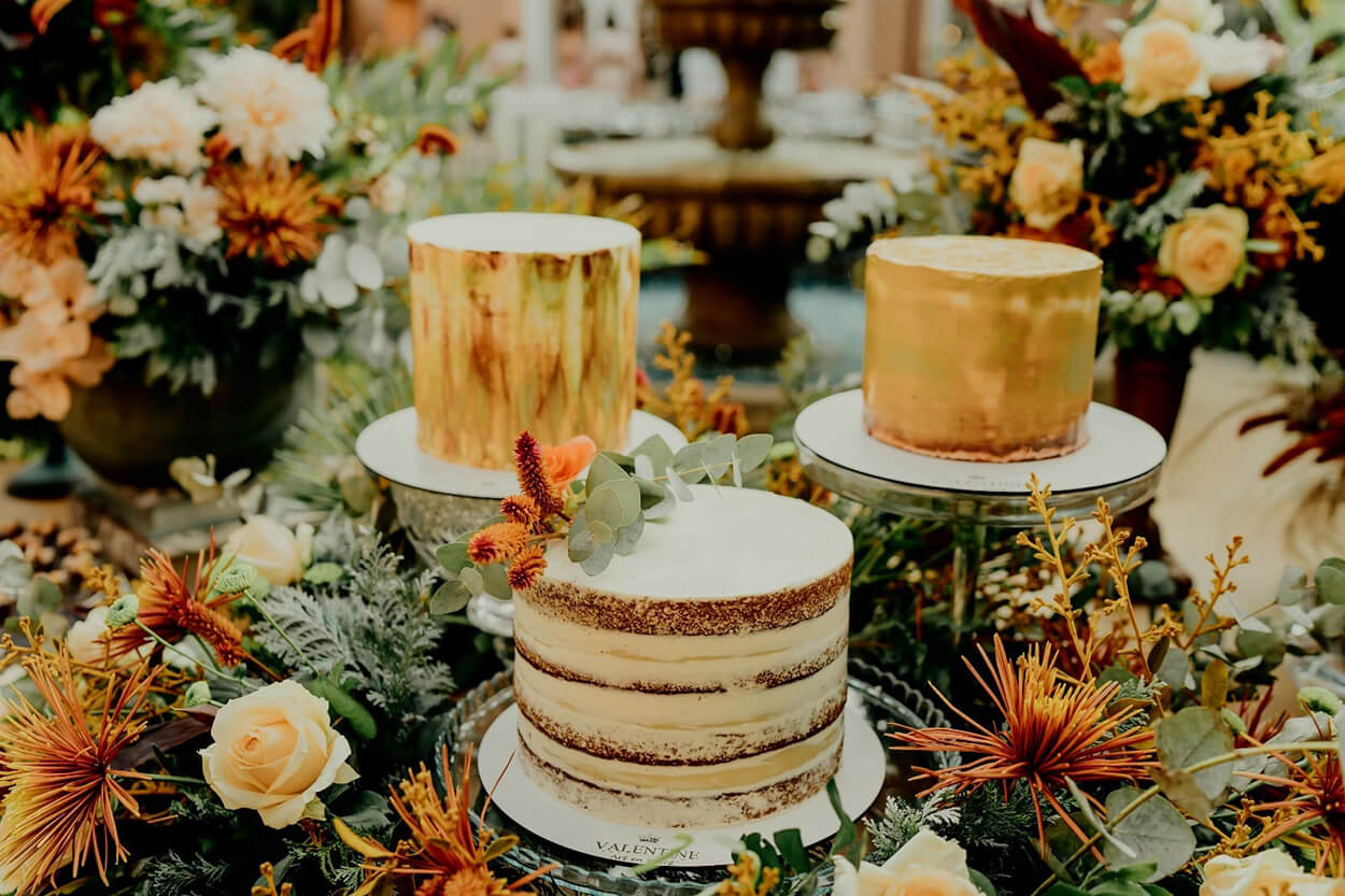 Mesa com trio de bolos de casamento e flores