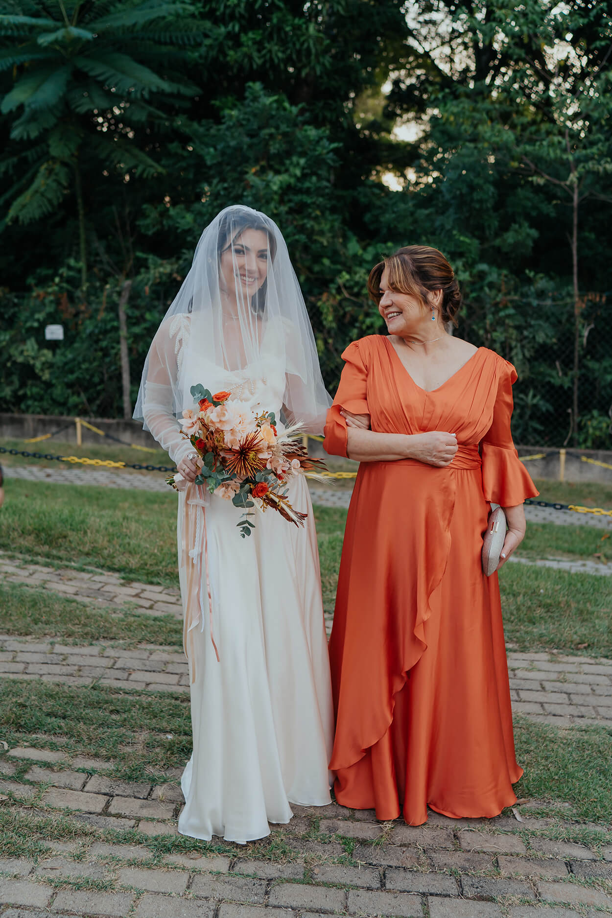 Entrada da noiva ao lado da mãe com vetsido laranja
