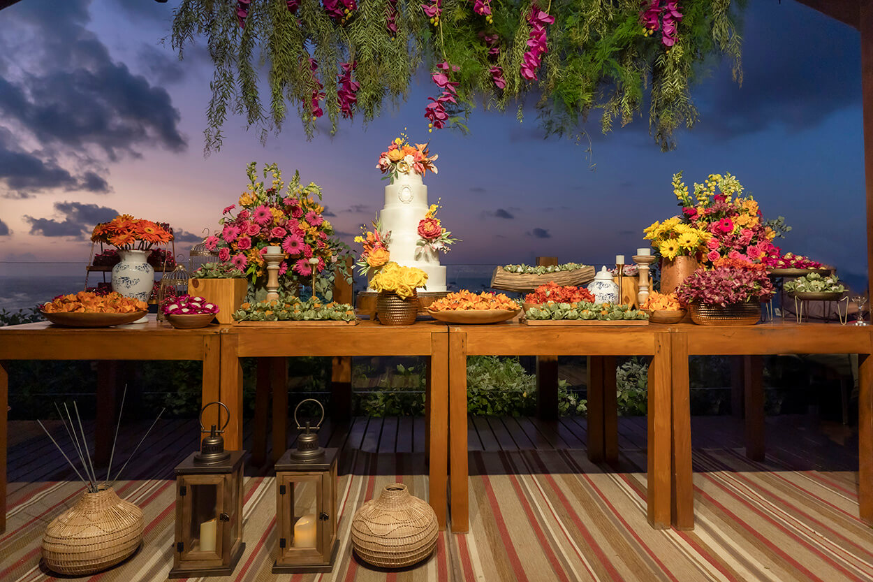 Mesa com bolo de casamento com flores e bandejas com doces